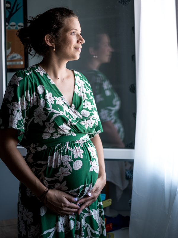 femme enceinte regardant par la fenêtre et avec son reflet