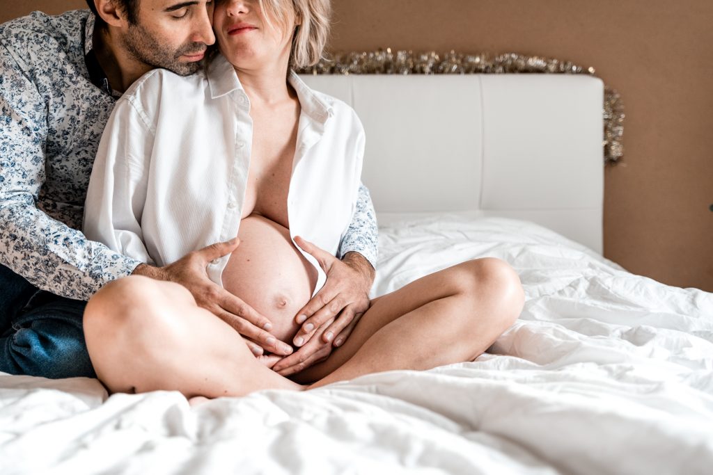 Amelie Charlet photographe seance photo grossesse couple de futurs parents sur le lit qui font un câlin