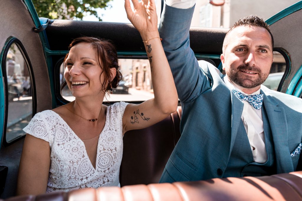 Amelie Charlet photographe reportage photo mariage couple faisant coucou pendant leur cortège en voiture