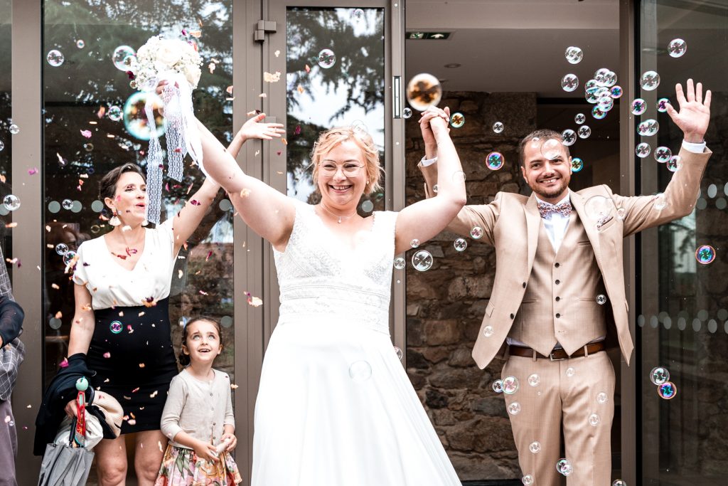 Amelie Charlet photographe reportage photo mariage couple de mariés qui sortent de la mairie avec des bulles